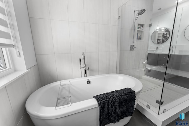 bathroom with tile walls, vanity, and shower with separate bathtub