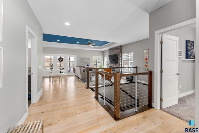 hallway featuring a tray ceiling and light wood-type flooring