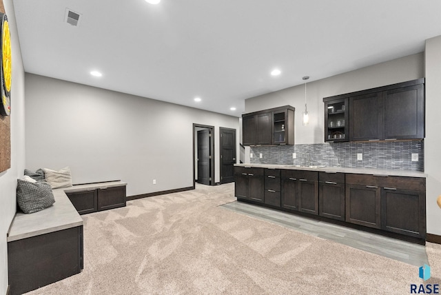 kitchen with sink, backsplash, hanging light fixtures, dark brown cabinetry, and light carpet