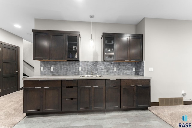 kitchen with tasteful backsplash, dark brown cabinetry, decorative light fixtures, and sink