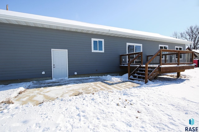 snow covered rear of property featuring a deck