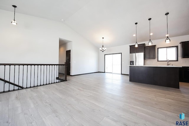 kitchen with open floor plan, light countertops, stainless steel refrigerator with ice dispenser, a center island, and pendant lighting