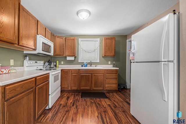 kitchen featuring dark wood-type flooring, white appliances, and sink