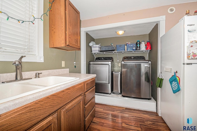 laundry area featuring dark wood-type flooring, washer and clothes dryer, and sink