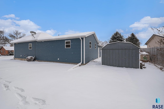 snow covered house featuring a storage unit