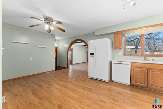 kitchen with white appliances, sink, and light hardwood / wood-style flooring