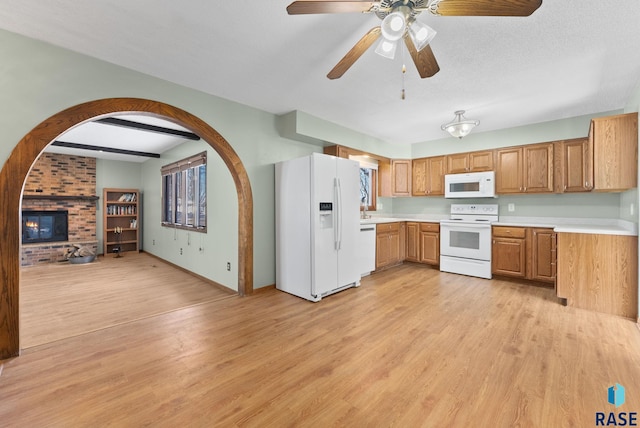 kitchen featuring white appliances, a textured ceiling, a brick fireplace, and light wood-type flooring