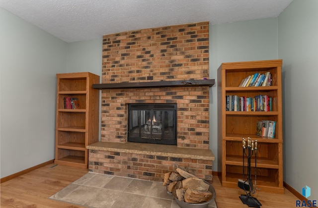 living room with a fireplace, a textured ceiling, and light wood-type flooring