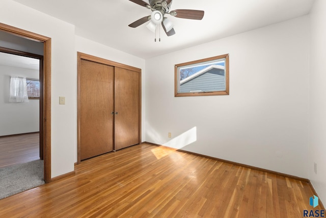 unfurnished bedroom with ceiling fan, a closet, and light wood-type flooring