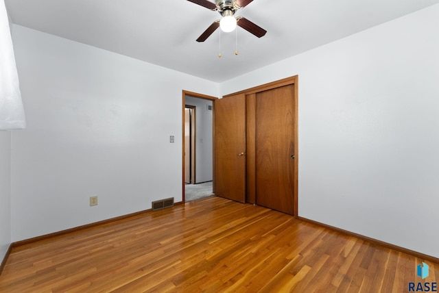 unfurnished bedroom featuring ceiling fan, light hardwood / wood-style floors, and a closet