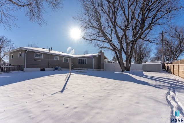 snow covered rear of property featuring a jacuzzi