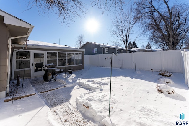 yard covered in snow with a sunroom