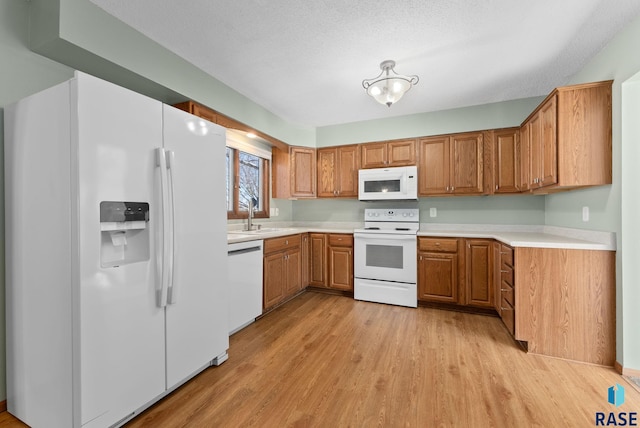 kitchen with sink, white appliances, light hardwood / wood-style flooring, and a textured ceiling