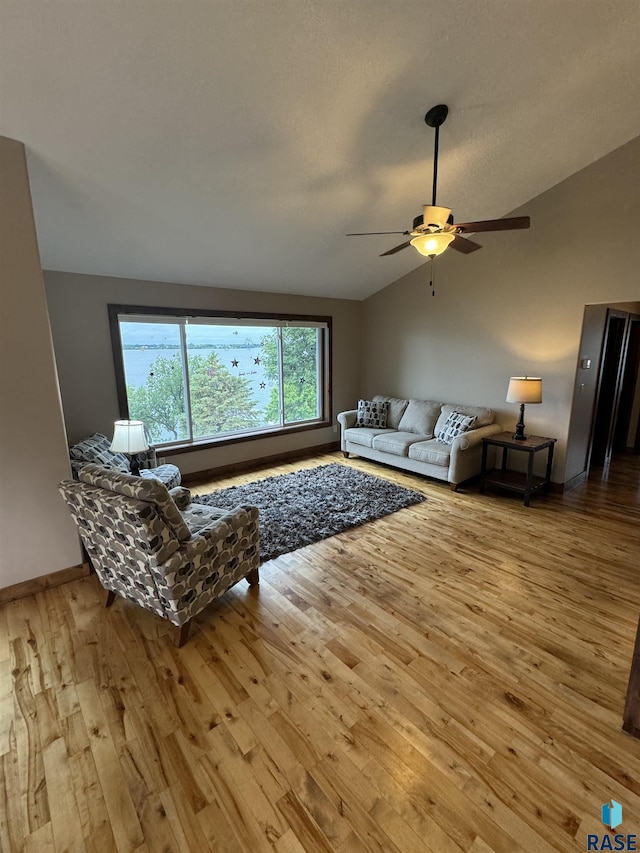 living room featuring ceiling fan, lofted ceiling, and wood-type flooring