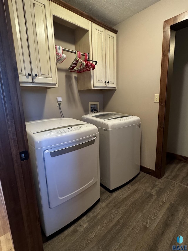 laundry room featuring dark wood-type flooring, washer and clothes dryer, cabinets, and a textured ceiling