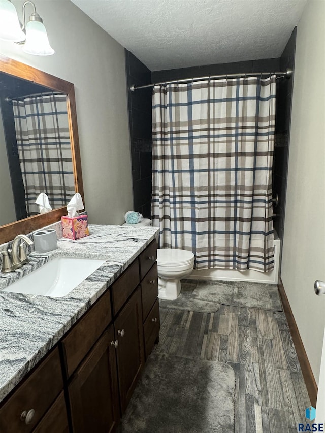 full bathroom featuring shower / bathtub combination with curtain, hardwood / wood-style flooring, vanity, a textured ceiling, and toilet