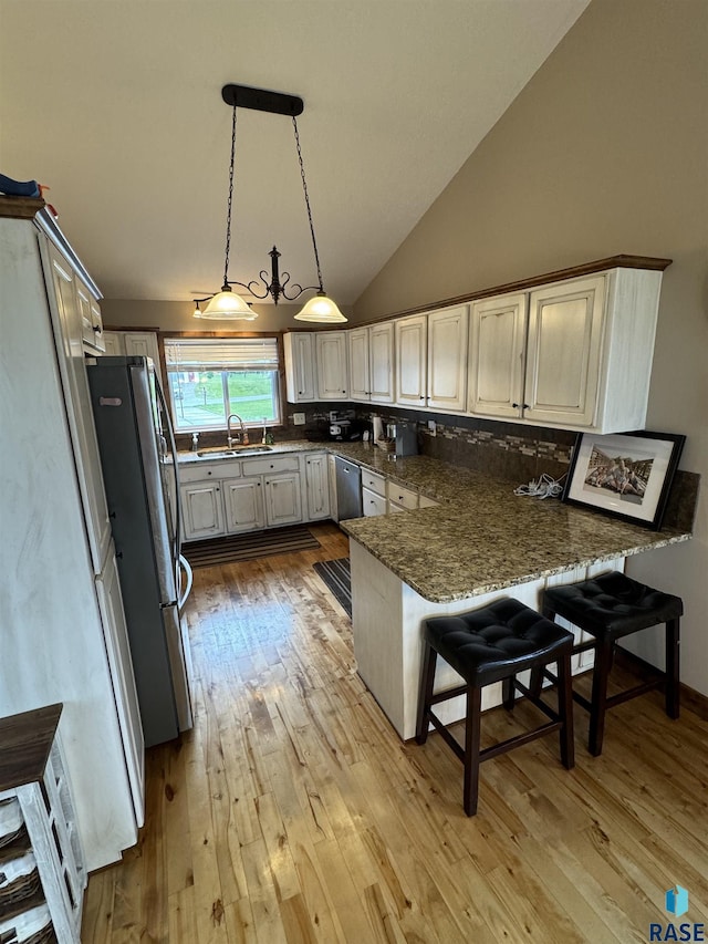 kitchen featuring pendant lighting, sink, kitchen peninsula, and a kitchen bar