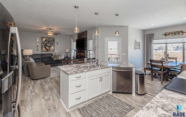 kitchen featuring stainless steel dishwasher, sink, pendant lighting, and white cabinets