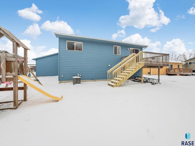 snow covered property with a playground and a deck