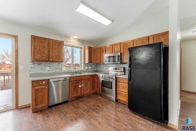 kitchen featuring vaulted ceiling, stainless steel appliances, dark wood-type flooring, and sink