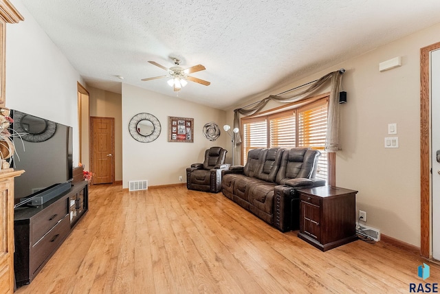 living room featuring lofted ceiling, a textured ceiling, ceiling fan, and light wood-type flooring