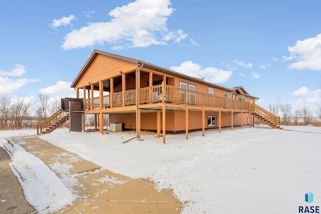 snow covered rear of property with a deck