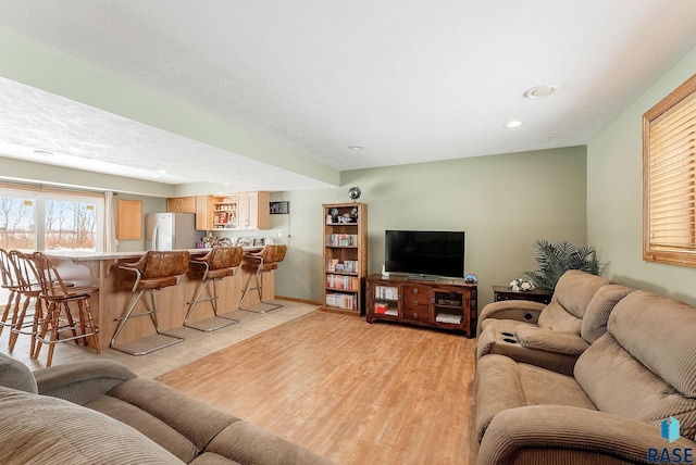 living room featuring light hardwood / wood-style floors, a textured ceiling, and bar area