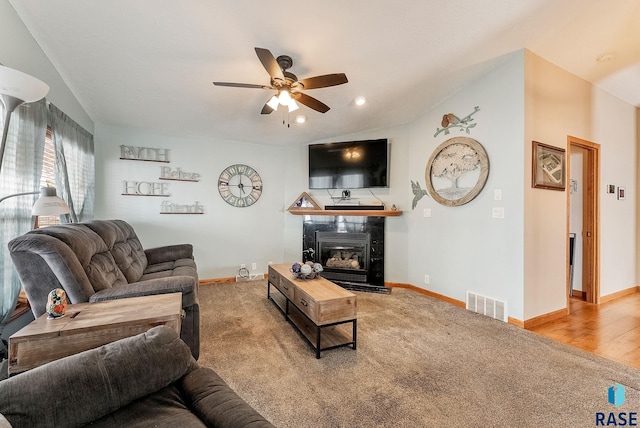 carpeted living room featuring a fireplace and ceiling fan