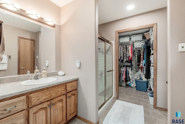 bathroom featuring a shower with shower door and vanity