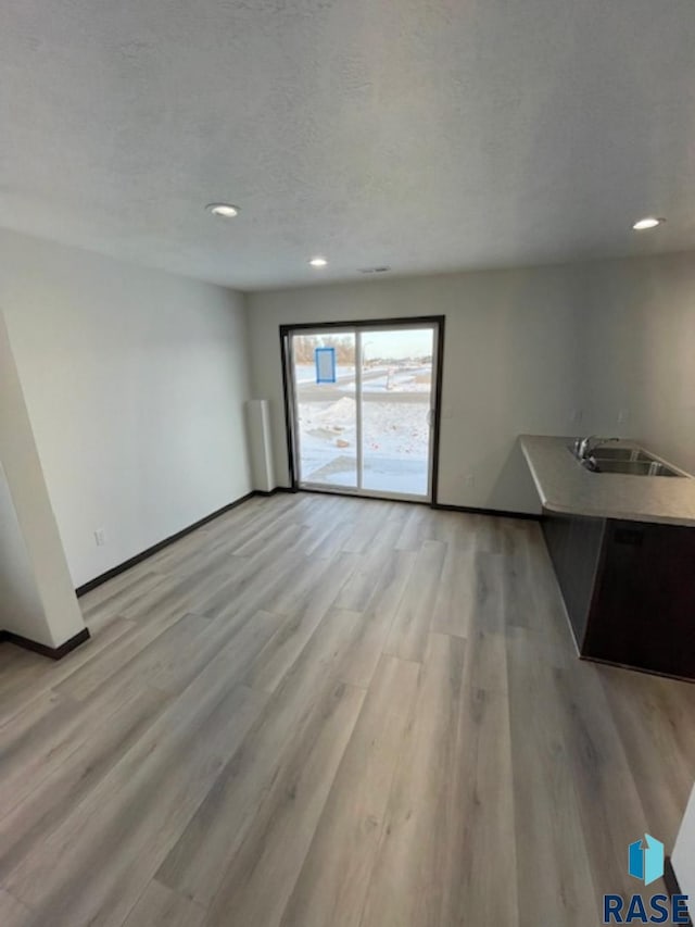 interior space with light wood-type flooring, sink, and a textured ceiling