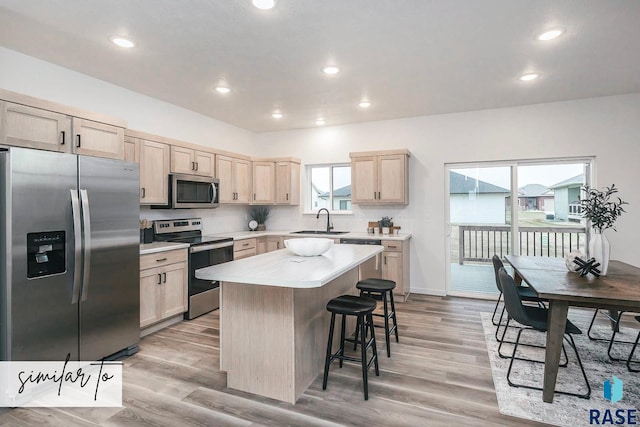 kitchen featuring a kitchen island, light hardwood / wood-style floors, stainless steel appliances, light brown cabinetry, and decorative backsplash