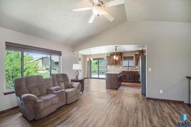 living room featuring sink, vaulted ceiling, ceiling fan, and wood-type flooring