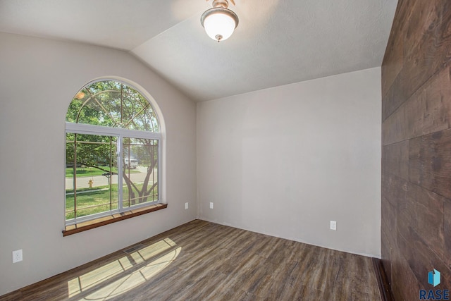 unfurnished room featuring hardwood / wood-style floors and vaulted ceiling