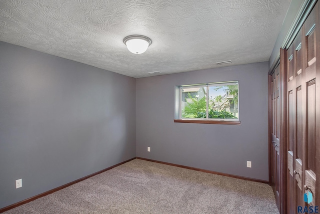 spare room featuring carpet floors and a textured ceiling