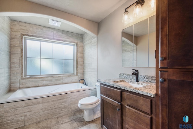 bathroom featuring tiled tub, vanity, toilet, and tile patterned floors