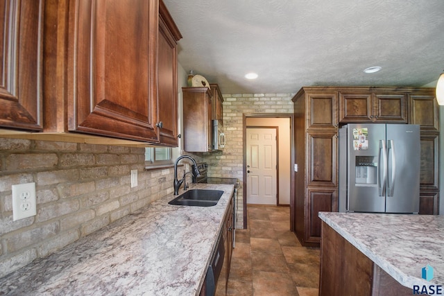 kitchen with stainless steel appliances, sink, backsplash, light stone counters, and a textured ceiling