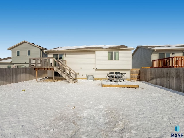 snow covered rear of property featuring a deck