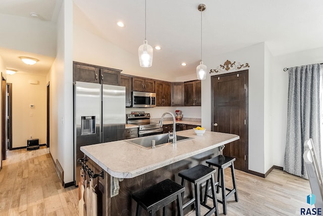 kitchen featuring sink, pendant lighting, stainless steel appliances, an island with sink, and dark brown cabinetry