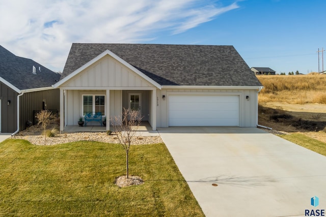 view of front of home featuring covered porch, a front yard, and a garage