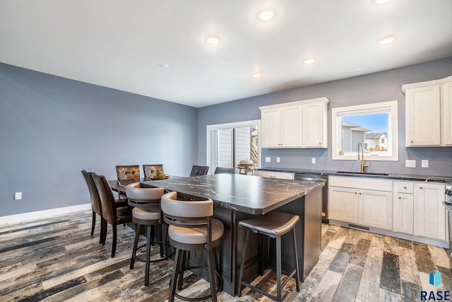 kitchen with white cabinets, sink, a kitchen island, and dark hardwood / wood-style flooring