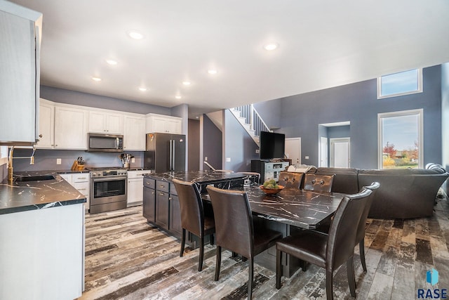 kitchen featuring white cabinetry, a center island, sink, appliances with stainless steel finishes, and hardwood / wood-style floors