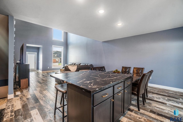 kitchen featuring dark brown cabinets, a kitchen breakfast bar, a kitchen island, and hardwood / wood-style flooring