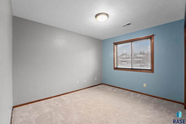 empty room with light carpet and a textured ceiling