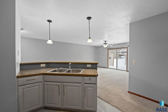 kitchen featuring sink, light carpet, gray cabinets, and decorative light fixtures