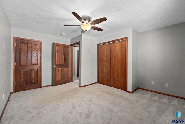 unfurnished bedroom featuring ceiling fan, a closet, a textured ceiling, and light colored carpet