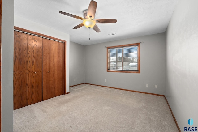 unfurnished bedroom featuring ceiling fan, a closet, a textured ceiling, and light colored carpet