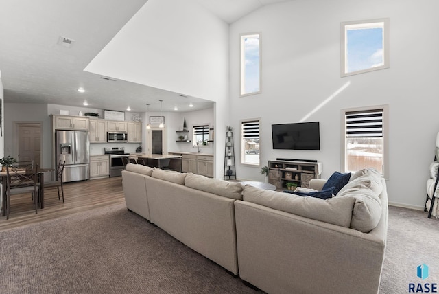 living room with dark carpet, a towering ceiling, and plenty of natural light