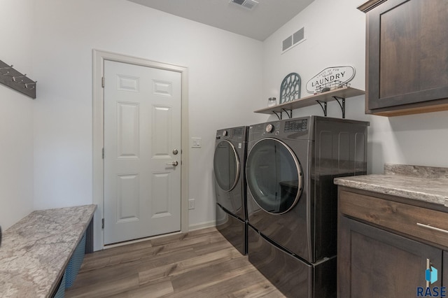 laundry area featuring cabinets, separate washer and dryer, and dark hardwood / wood-style floors