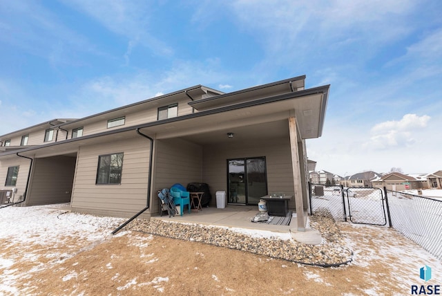 snow covered rear of property featuring a patio area