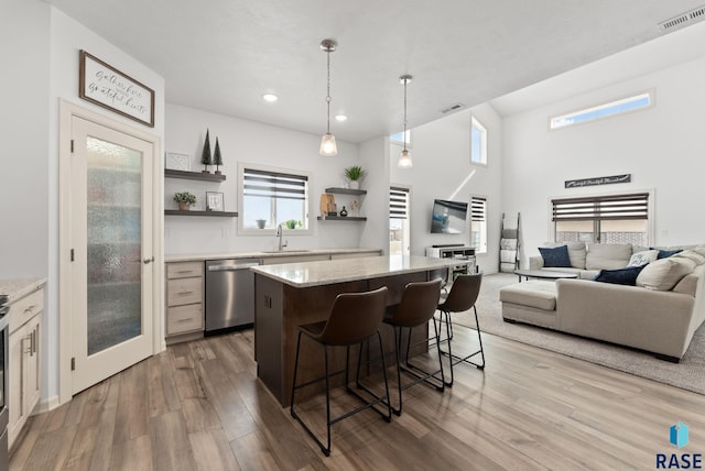 kitchen featuring decorative light fixtures, a kitchen island, sink, dishwasher, and a kitchen bar